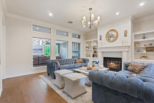 10003 Willow Bend Dr, Woodway, TX 76712 - living area featuring crown molding, a chandelier, built in features, wood finished floors, and a glass covered fireplace