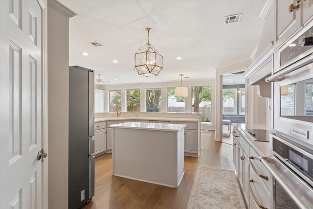 10003 Willow Bend Dr, Woodway, TX 76712 - kitchen with stainless steel appliances, a center island, light countertops, light wood-type flooring, and hanging light fixtures