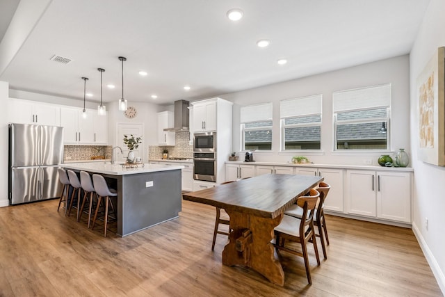 313 Savannah Ln, Oak Point, TX 75068 - kitchen with appliances with stainless steel finishes, wall chimney range hood, tasteful backsplash, healthy amount of natural light, and recessed lighting
