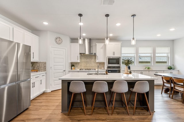 313 Savannah Ln, Oak Point, TX 75068 - kitchen with appliances with stainless steel finishes, wall chimney range hood, a kitchen island with sink, tasteful backsplash, and white cabinets