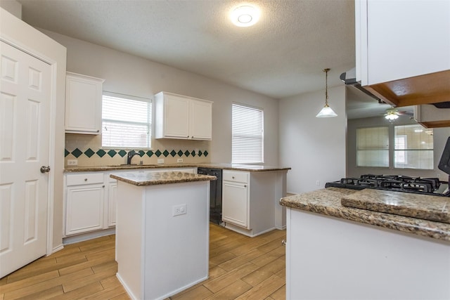 738 Opal Ln, Mesquite, TX 75149 - kitchen with dishwasher, a center island, light wood-style flooring, white cabinets, and a textured ceiling