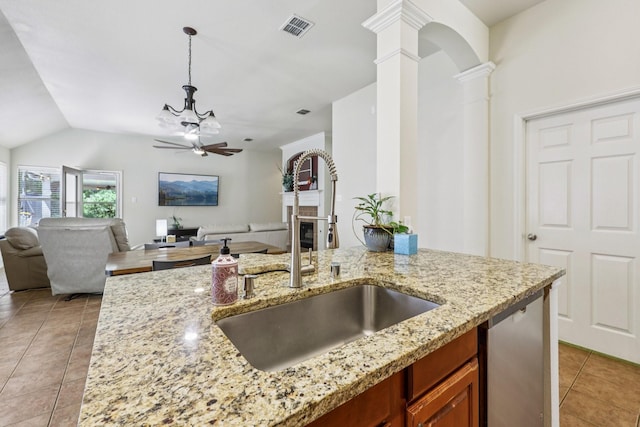 504 Lake Point Dr, Little Elm, TX 75068 - kitchen with brown cabinets, light tile patterned floors, dishwasher, open floor plan, and ornate columns