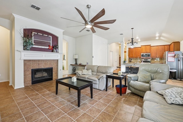 504 Lake Point Dr, Little Elm, TX 75068 - living area featuring a ceiling fan, arched walkways, vaulted ceiling, tile patterned flooring, and a tile fireplace