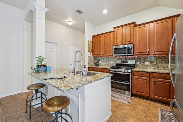 504 Lake Point Dr, Little Elm, TX 75068 - kitchen featuring stainless steel appliances, ornate columns, backsplash, light stone counters, and light tile patterned floors