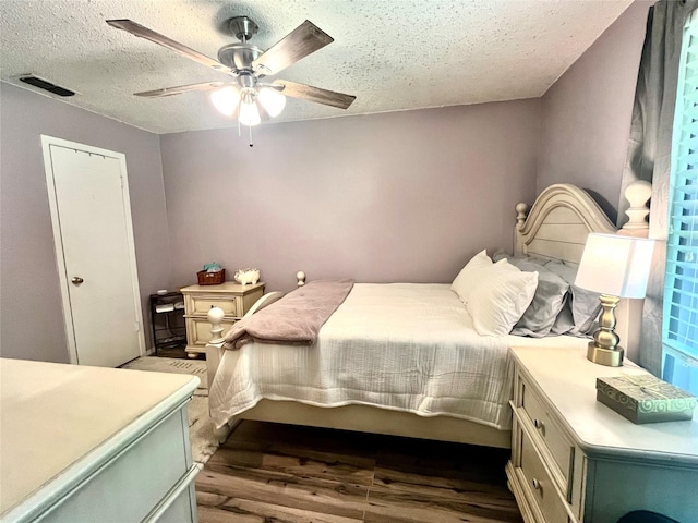 309 Bellaire Dr, Denton, TX 76209 - bedroom featuring a textured ceiling, dark wood finished floors, and a ceiling fan