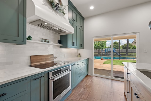 1402 Summer Dell Ct, Keller, TX 76262 - kitchen featuring oven, custom exhaust hood, green cabinetry, decorative backsplash, and light stone countertops