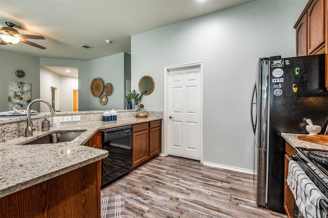 9938 Wethers Field Cir, Providence Village, TX 76227 - kitchen with black appliances, light wood-style floors, ceiling fan, light stone counters, and brown cabinets