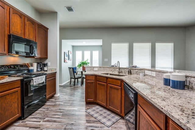 9938 Wethers Field Cir, Providence Village, TX 76227 - kitchen featuring black appliances, light wood-style floors, and light stone counters