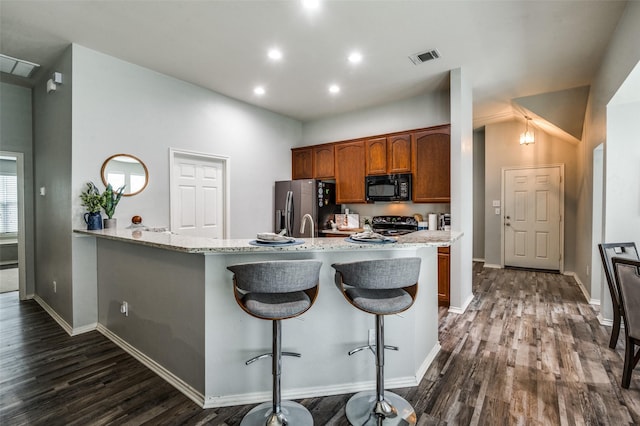 9938 Wethers Field Cir, Providence Village, TX 76227 - kitchen featuring black appliances, dark wood-style floors, light stone countertops, a kitchen breakfast bar, and recessed lighting