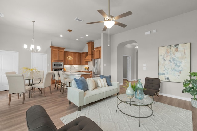 813 Louisville Rd, Savannah, TX 76227 - living room with arched walkways, light wood-style floors, a ceiling fan, lofted ceiling, and a chandelier