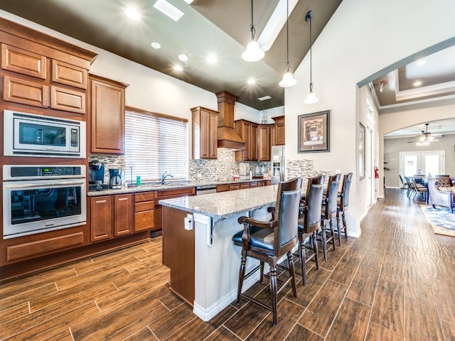 813 Louisville Rd, Savannah, TX 76227 - kitchen featuring appliances with stainless steel finishes, arched walkways, a breakfast bar area, dark wood-style floors, and light stone counters