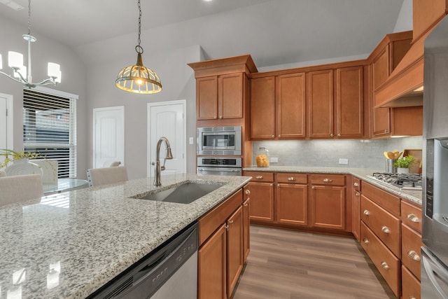 813 Louisville Rd, Savannah, TX 76227 - kitchen featuring appliances with stainless steel finishes, vaulted ceiling, brown cabinets, a chandelier, and tasteful backsplash