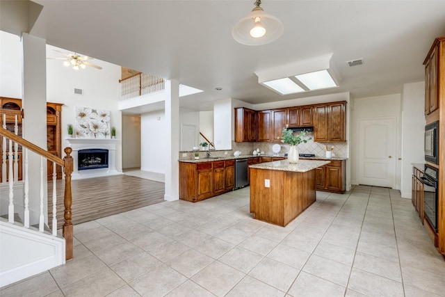 4513 Southpointe Dr, Richardson, TX 75082 - kitchen featuring black appliances, a fireplace with raised hearth, light tile patterned floors, open floor plan, and a kitchen island