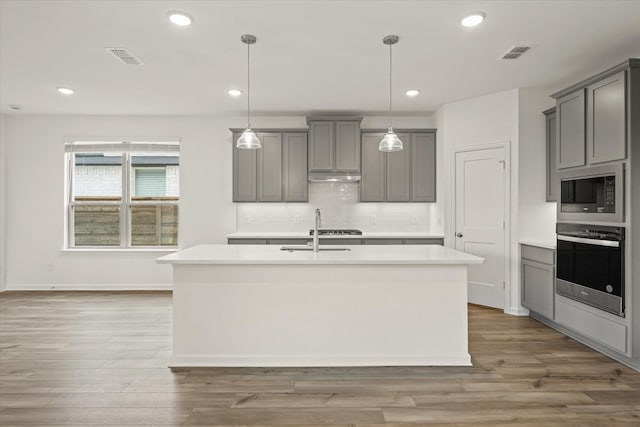 1900 Twisted Tree Ln, Mesquite, TX 75181 - kitchen featuring appliances with stainless steel finishes, gray cabinets, a kitchen island with sink, light countertops, and recessed lighting