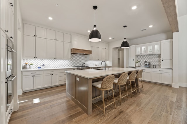 1454 Sunset Point Dr, Flower Mound, TX 75022 - kitchen featuring custom exhaust hood, decorative backsplash, white cabinetry, a breakfast bar area, and an island with sink