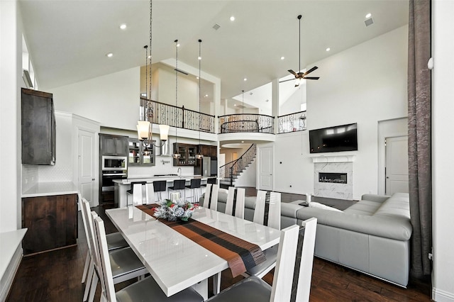 1018 Cascading Creek Dr, Rockwall, TX 75087 - dining area with high vaulted ceiling, dark wood finished floors, a premium fireplace, a ceiling fan, and stairway
