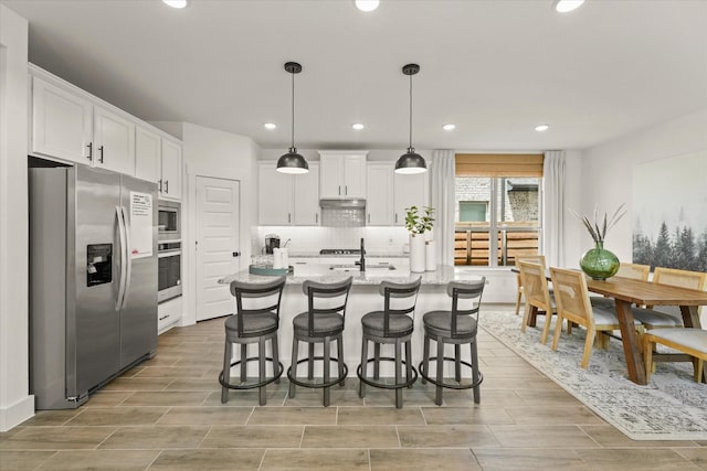 2100 Jade Forest Ln, Mesquite, TX 75181 - kitchen featuring appliances with stainless steel finishes, white cabinetry, a kitchen breakfast bar, wood tiled floors, and recessed lighting