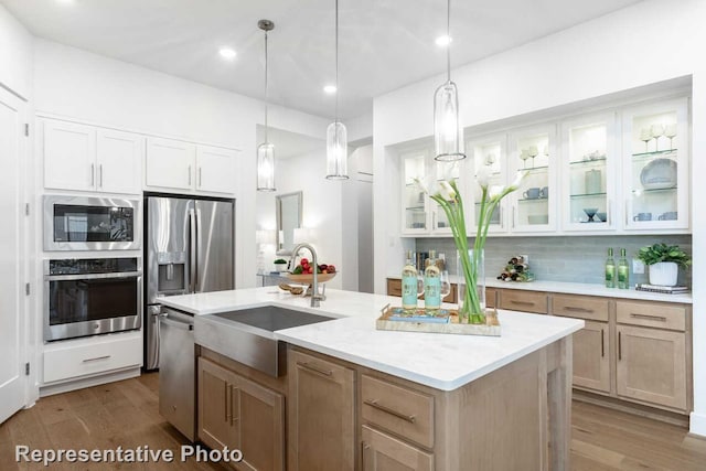 3613 Barrel Ln, Aubrey, TX 76227 - kitchen featuring appliances with stainless steel finishes, wood finished floors, a center island with sink, glass insert cabinets, and backsplash