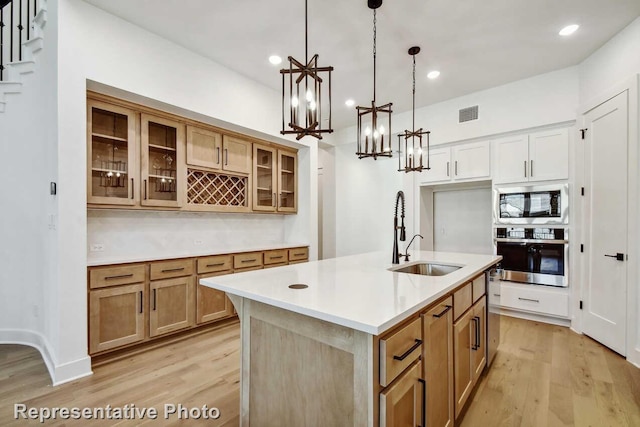 3613 Barrel Ln, Aubrey, TX 76227 - kitchen with stainless steel appliances, light wood-style floors, glass insert cabinets, light countertops, and decorative light fixtures