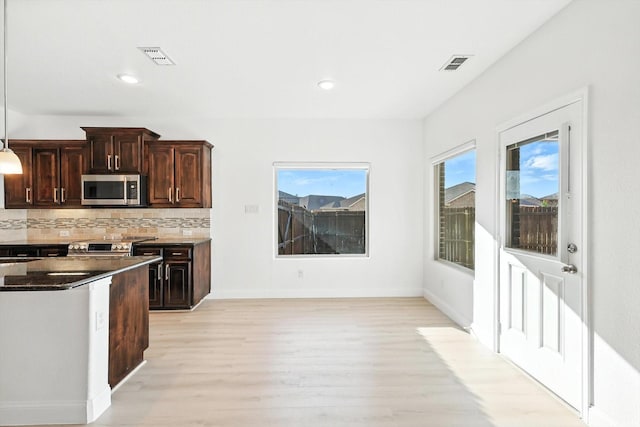 3901 Tule Ranch Rd, Fort Worth, TX 76262 - kitchen featuring stainless steel microwave, light wood-style floors, stove, backsplash, and dark brown cabinets
