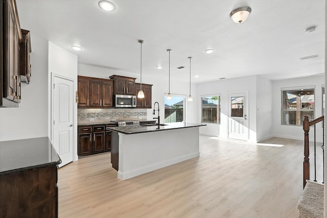 3901 Tule Ranch Rd, Fort Worth, TX 76262 - kitchen featuring stainless steel microwave, light wood finished floors, dark brown cabinets, tasteful backsplash, and recessed lighting