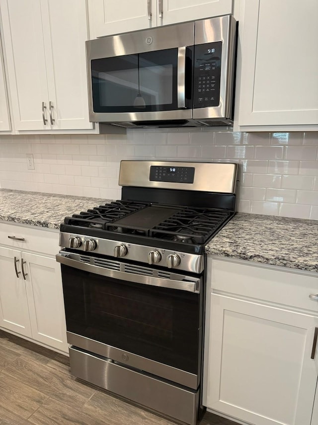 724 Esau Ave, Bossier City, LA 71111 - kitchen with stainless steel appliances, white cabinets, wood finished floors, and decorative backsplash