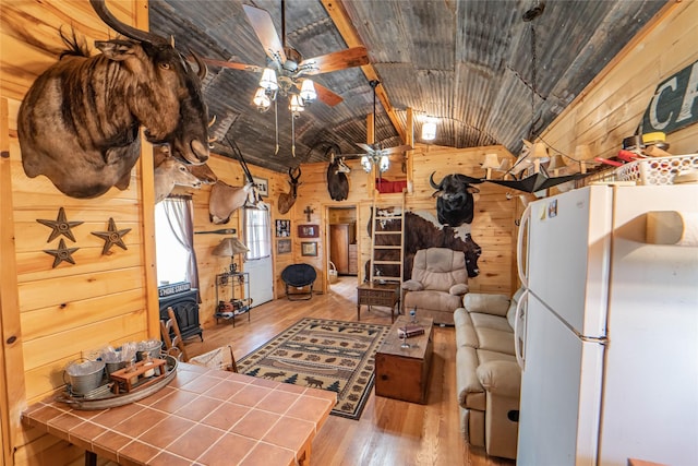 9504 County Road 197, Breckenridge, TX 76424 - living area featuring a wood stove, wooden walls, wood-type flooring, vaulted ceiling, and a ceiling fan