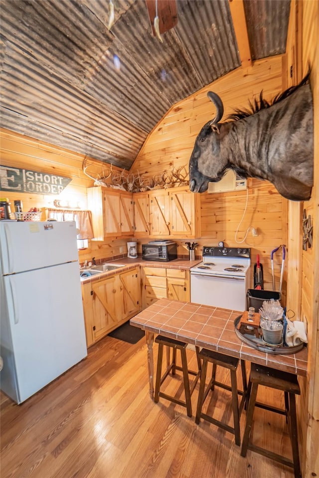 9504 County Road 197, Breckenridge, TX 76424 - kitchen with white appliances, tile countertops, light brown cabinetry, wood walls, and lofted ceiling