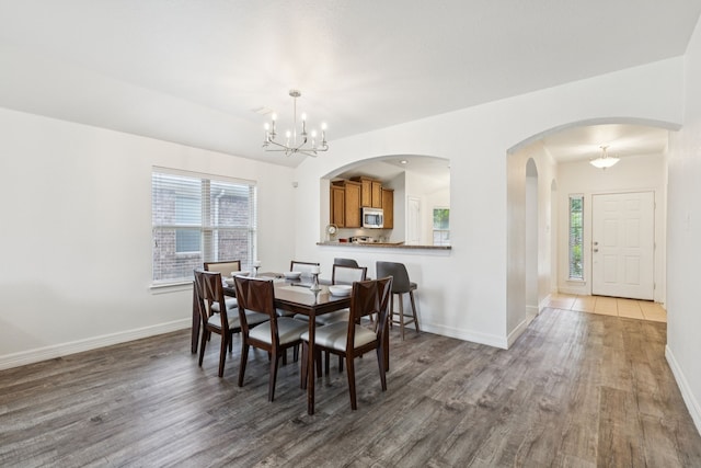 913 Lovebird Ln, Little Elm, TX 75068 - dining area with wood finished floors, healthy amount of natural light, a chandelier, and arched walkways