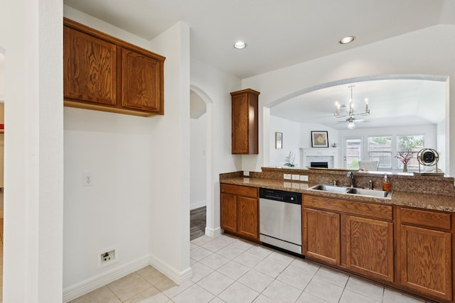 913 Lovebird Ln, Little Elm, TX 75068 - kitchen featuring stainless steel dishwasher, a ceiling fan, arched walkways, a fireplace, and brown cabinetry