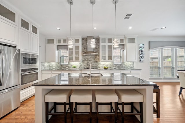 4652 Man O War Rd, Carrollton, TX 75010 - kitchen with appliances with stainless steel finishes, wall chimney exhaust hood, decorative backsplash, a breakfast bar area, and recessed lighting