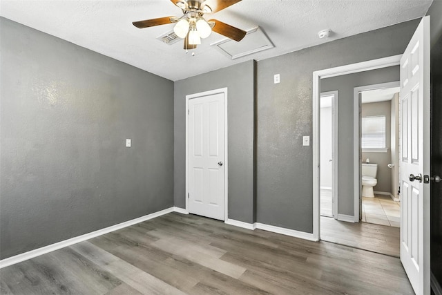 216 N Dobson St, Burleson, TX 76028 - unfurnished bedroom featuring wood finished floors, attic access, ceiling fan, and a textured ceiling