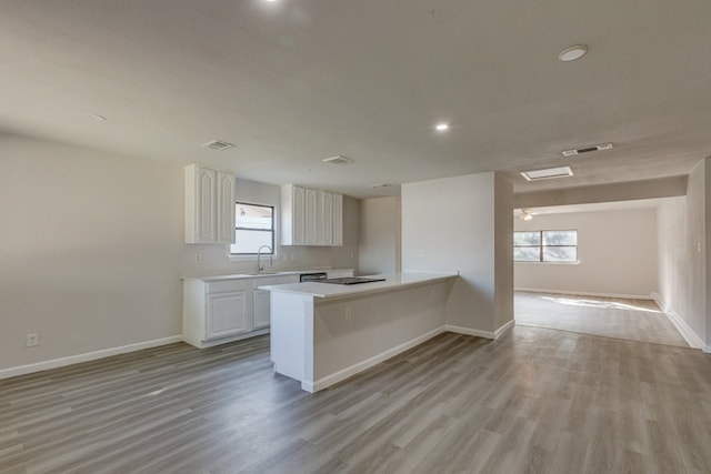 1006 Sleepy Hollow Dr, Garland, TX 75043 - kitchen featuring light countertops, white cabinetry, light wood-type flooring, recessed lighting, and a peninsula