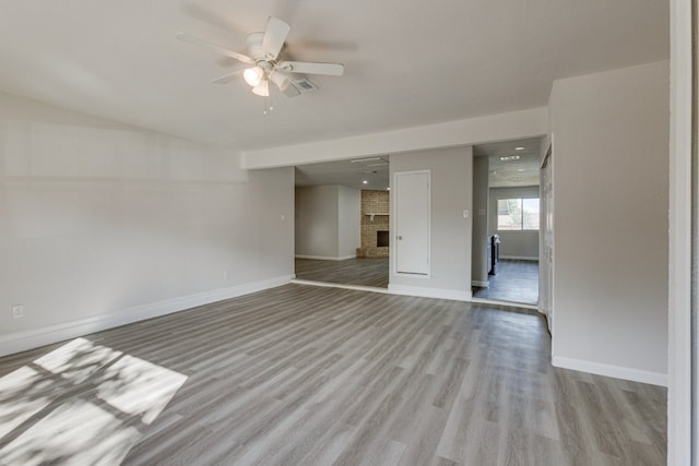 1006 Sleepy Hollow Dr, Garland, TX 75043 - empty room with a ceiling fan, wood finished floors, and a brick fireplace