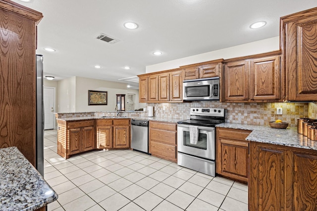 102 Southfork Cir, Pottsboro, TX 75076 - kitchen with appliances with stainless steel finishes, a peninsula, decorative backsplash, light tile patterned flooring, and recessed lighting