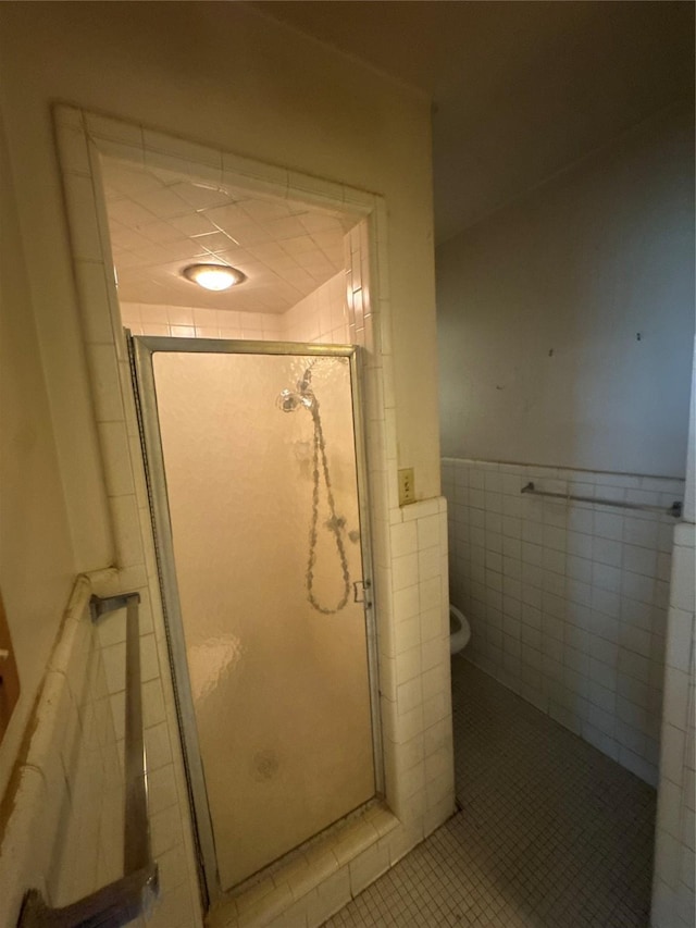 817 Brook Valley Ln, Dallas, TX 75232 - bathroom featuring a stall shower, tile walls, a wainscoted wall, and tile patterned floors