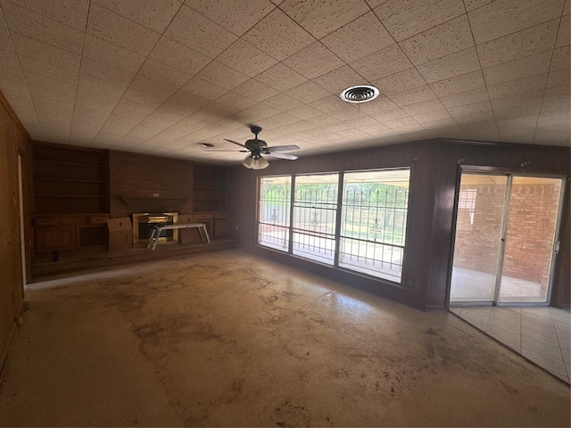 817 Brook Valley Ln, Dallas, TX 75232 - unfurnished living room with concrete flooring, ceiling fan, a wood stove, and built in shelves