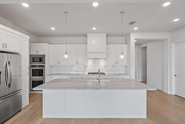 7020 Union Park Blvd E, Little Elm, TX 76227 - kitchen with stainless steel appliances, backsplash, white cabinetry, light stone countertops, and light wood-style floors