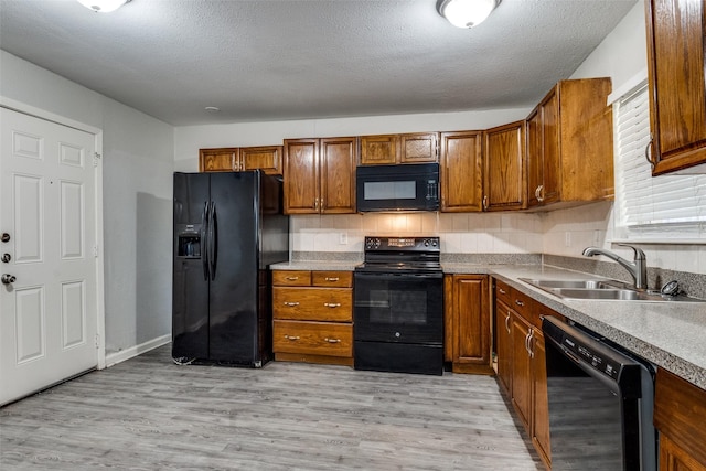 4137 Salem Dr, Garland, TX 75043 - kitchen featuring black appliances, brown cabinets, light wood finished floors, a textured ceiling, and light countertops