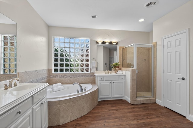 1709 Blair Ct, Carrollton, TX 75010 - bathroom with two vanities, a stall shower, a garden tub, and wood finished floors