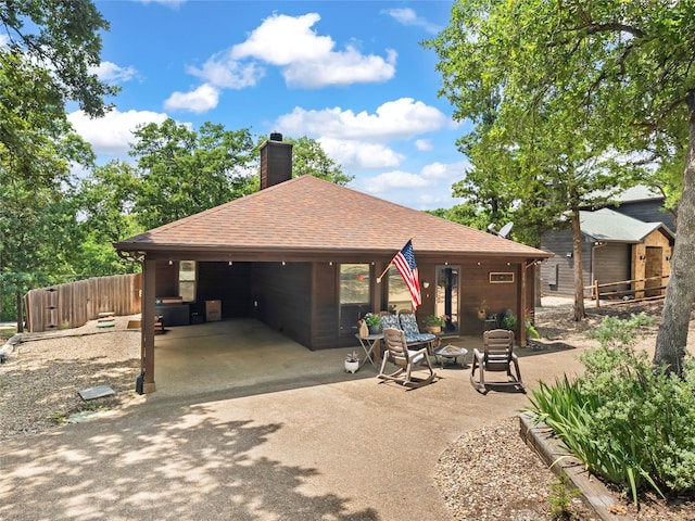 153 Bridlepath Dr, Pottsboro, TX 75076 - back of house with roof with shingles, a chimney, driveway, a carport, and a patio area