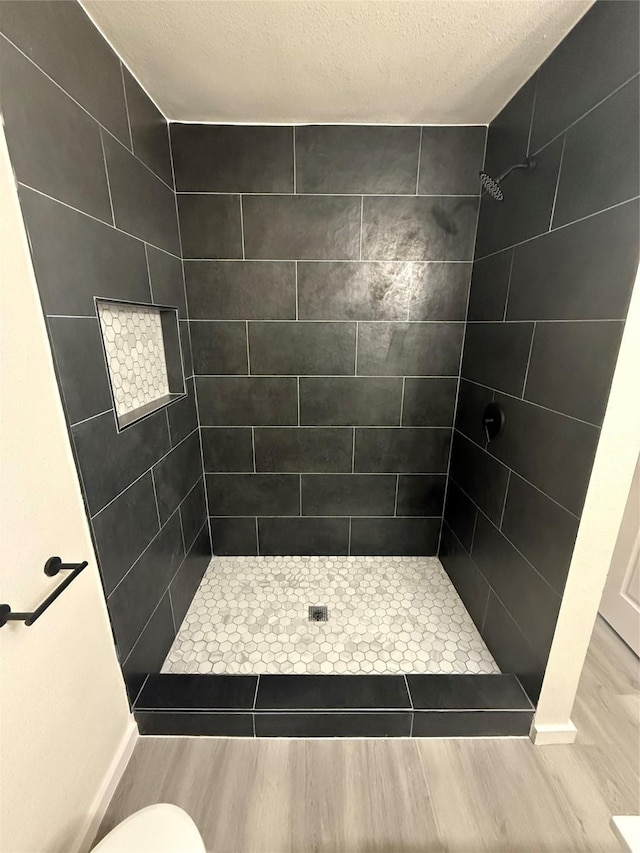 2703 Hollow Bnd, Mesquite, TX 75150 - full bathroom featuring wood finished floors, a tile shower, and a textured ceiling