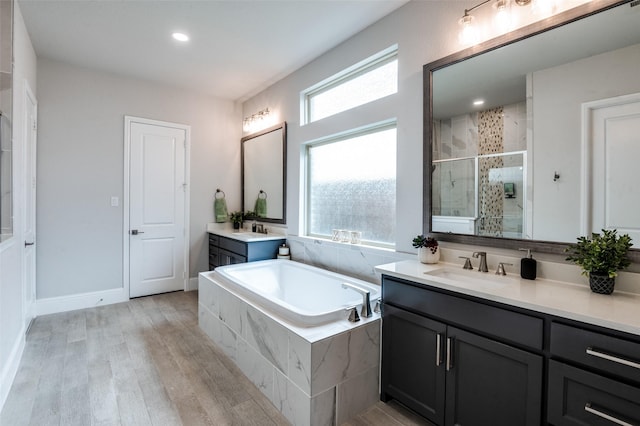 840 Redstem Dr, Prosper, TX 75078 - bathroom featuring a stall shower, two vanities, a bath, wood finished floors, and recessed lighting