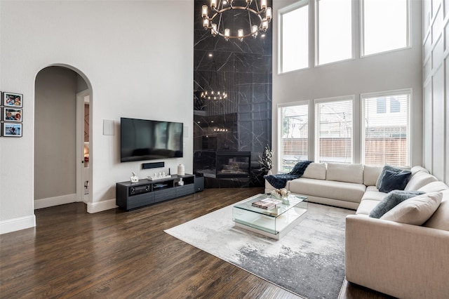 840 Redstem Dr, Prosper, TX 75078 - living room featuring a towering ceiling, arched walkways, a chandelier, plenty of natural light, and wood finished floors