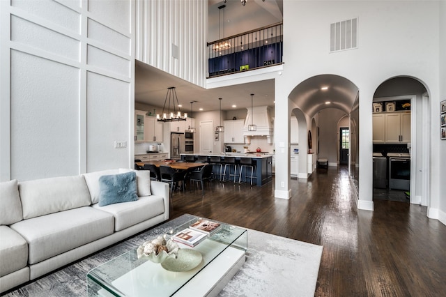840 Redstem Dr, Prosper, TX 75078 - living area featuring arched walkways, dark wood-type flooring, a high ceiling, and a chandelier
