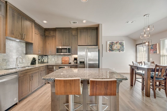421 W Holford St, Pilot Point, TX 76258 - kitchen with stainless steel appliances, light wood finished floors, a center island, backsplash, and recessed lighting