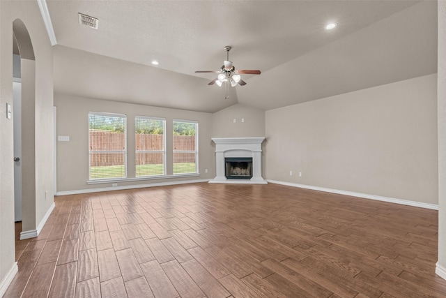 842 Randall Rd, Weatherford, TX 76087 - unfurnished living room with a ceiling fan, wood finished floors, arched walkways, lofted ceiling, and a fireplace with raised hearth