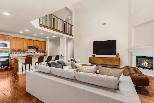 4560 Cheetah Trl, Frisco, TX 75034 - living area featuring dark wood-type flooring, recessed lighting, a towering ceiling, and a glass covered fireplace