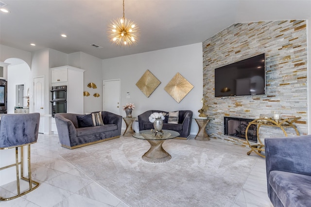 1400 Ambrose Dr, Allen, TX 75002 - living area with arched walkways, a stone fireplace, light marble finish floors, recessed lighting, and a chandelier