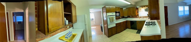 112 Jenny Kay Ln, Irving, TX 75060 - kitchen featuring black appliances, light countertops, vaulted ceiling, brown cabinetry, and a warming drawer